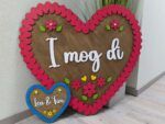 Decorative display with a large brown heart and pink scalloped border, flower and leaf cutouts, and white cursive text; a blue circular frame with small yellow flowers sits at the bottom.