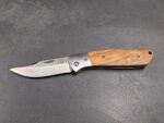 Folding knife with a wooden handle and extended blade resting on a dark textured surface.